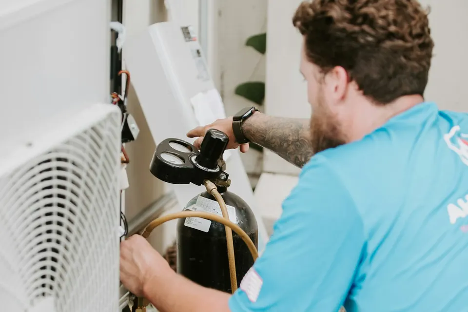 A technician servicing an outdoor air conditioning unit