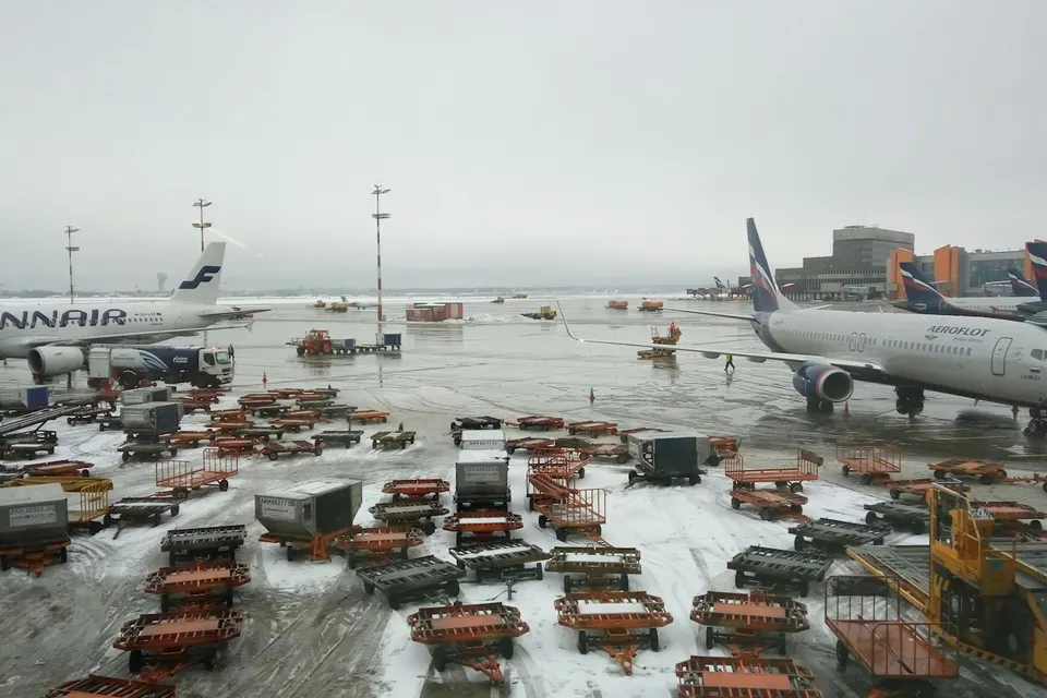 Airliners and rows of cargo dollies on a snowy airport apron
