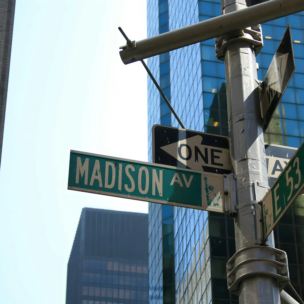 Green street signs for Madison Avenue and East 53rd Street against Midtown Manhattan office towers